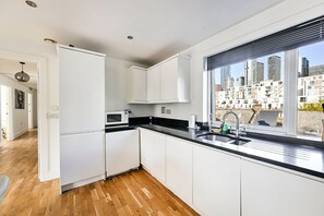 Een moderne keuken met witte kasten, een zwart aanrecht en een raam met uitzicht op de stad.