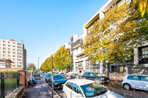 Een straat met geparkeerde auto's en meerlaagsgebouwen, waaronder een parkeergarage.