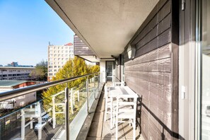 Een balkon met een hekwerk, een tafel en stoelen.