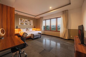 Una camera d'albergo con un letto, una scrivania, una sedia e una grande finestra.