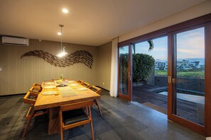 Una sala da pranzo moderna con un grande tavolo in legno, sedie e un elemento decorativo a parete.