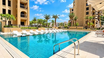 A swimming pool with lounge chairs and a clear sky.