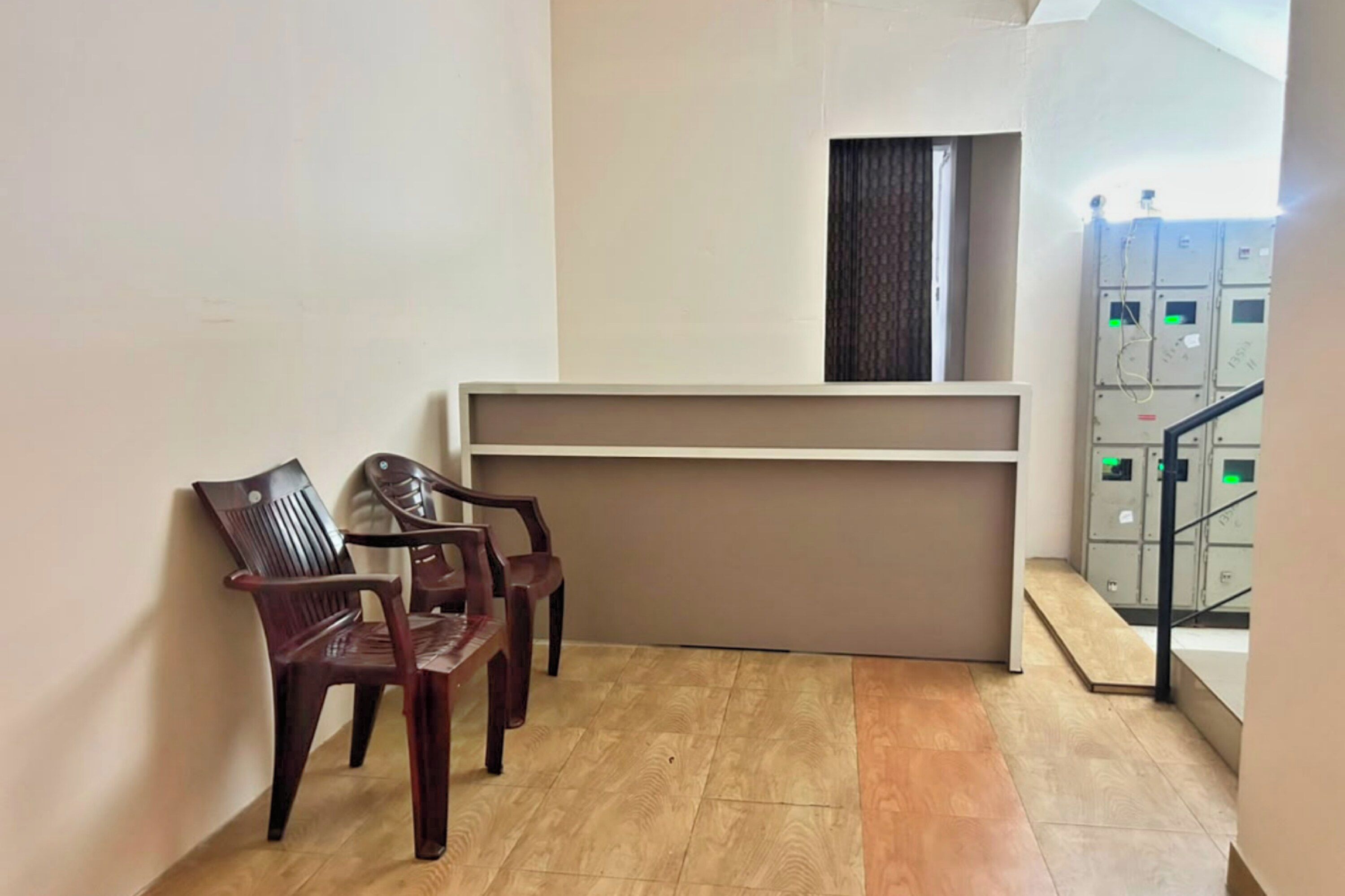 Zona de recepción con mostrador, dos sillas de madera y una escalera que sube a un piso superior.