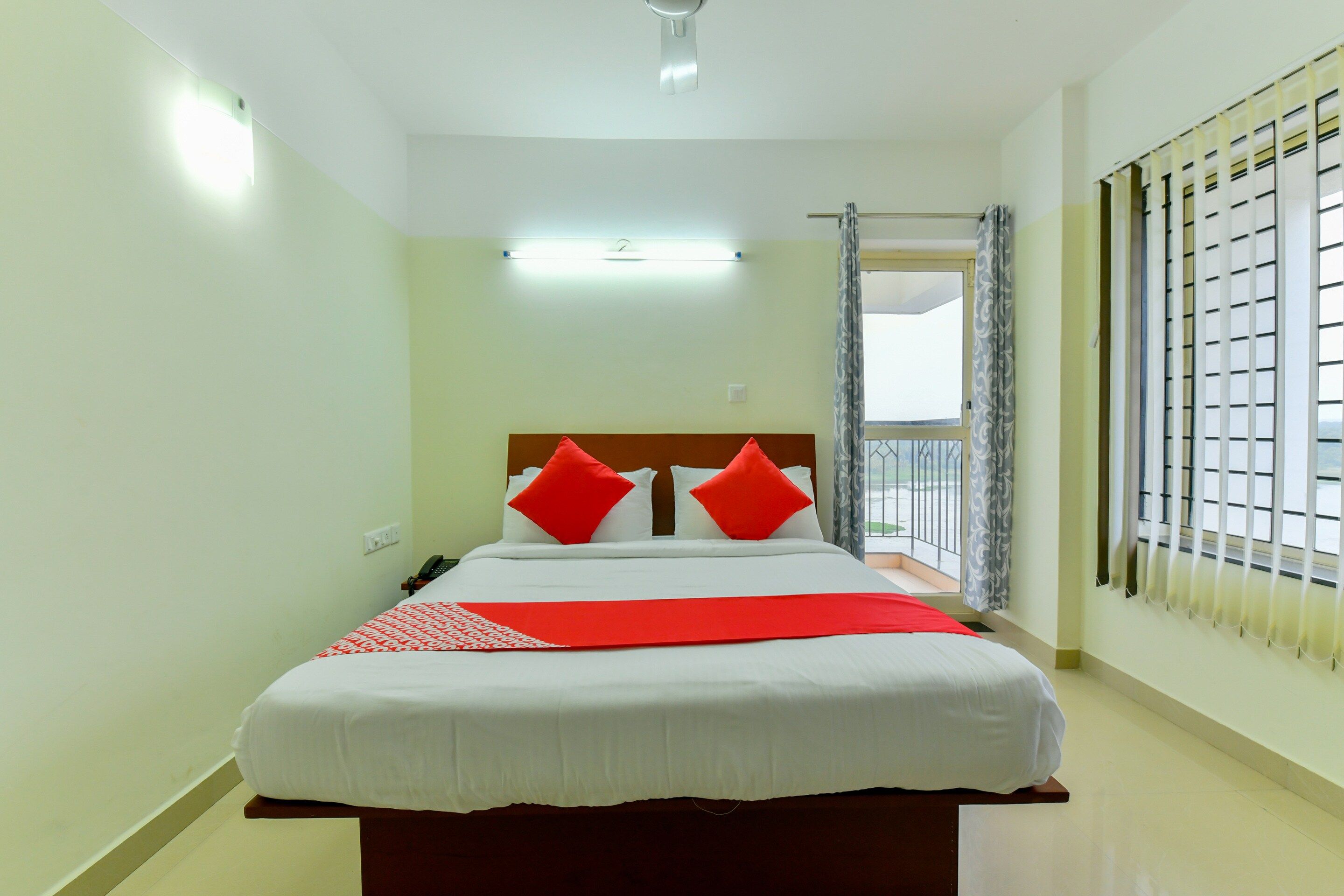 Quarto de hotel com cama, telefone e janela com persianas.