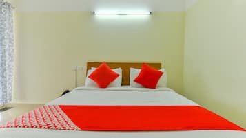 A hotel room with a bed, a red throw blanket, and a white headboard.