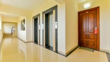 Un pasillo con una puerta de madera marcada '13 SA1' y tres ascensores.