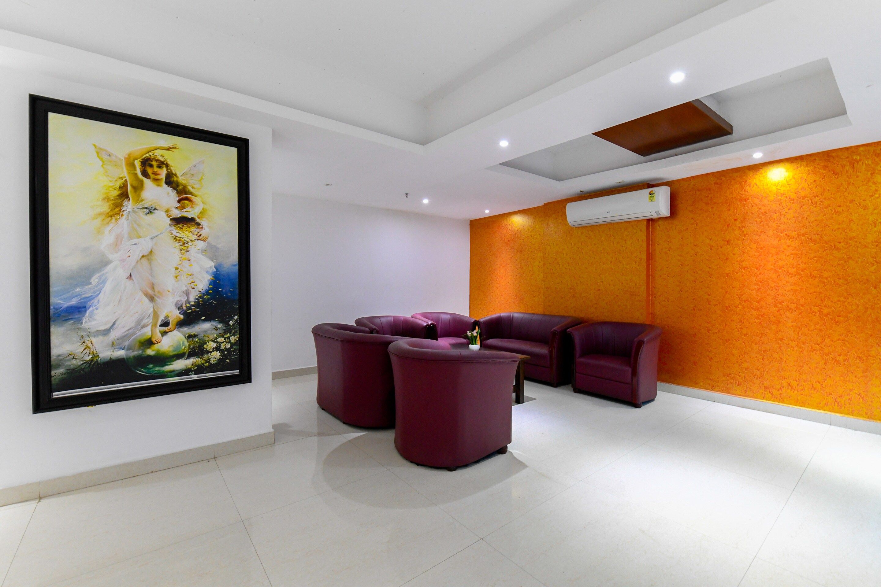 A modern interior with a large framed painting, a seating area with purple chairs, and an air conditioning unit on the wall.
