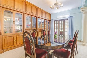 Une salle à manger avec une table ronde, six chaises et des meubles en bois dotés de portes en verre.