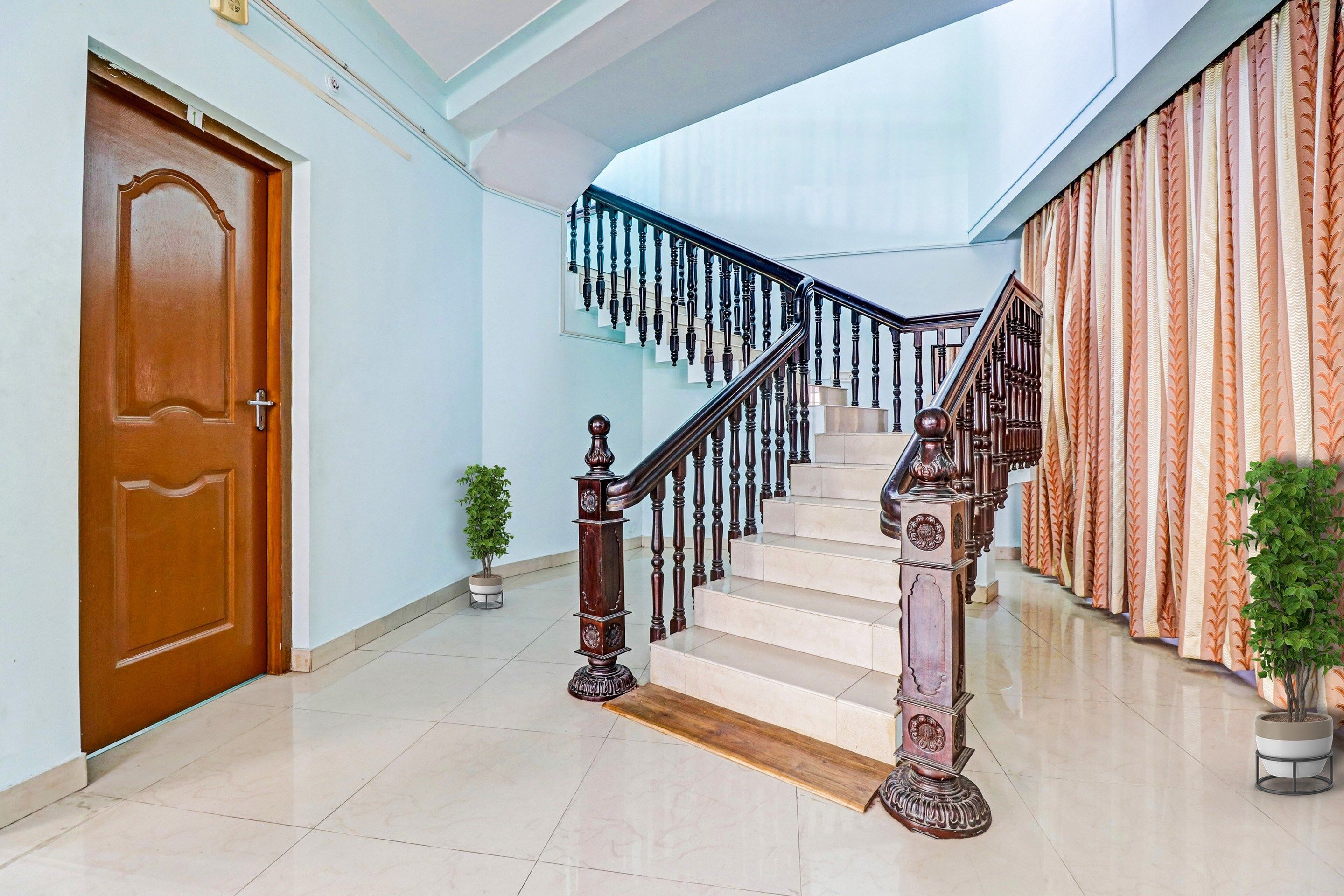 Una escalera con barandilla de madera y balaustrada negra, que conduce a un piso superior.