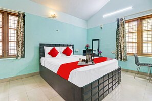 Une chambre d’hôtel avec un lit, une table de chevet avec un plateau, une chaise et une fenêtre avec des rideaux.