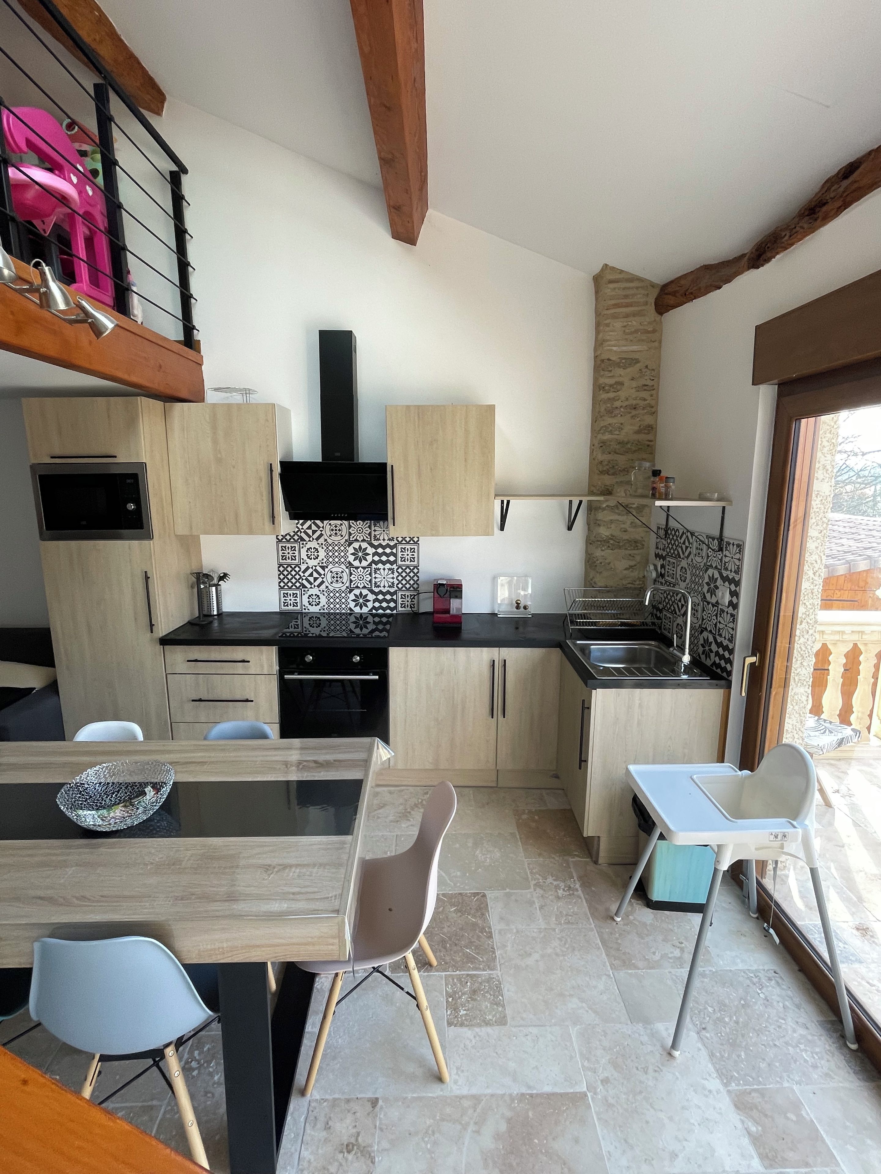 Eine moderne Küche mit Holzausziehtüren, einer schwarzen Arbeitsplatte und einer gemusterten Spritzschutzwand.