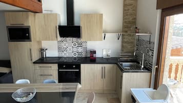 Eine moderne Küche mit Holzausziehtüren, einer schwarzen Arbeitsplatte und einer gemusterten Spritzschutzwand.