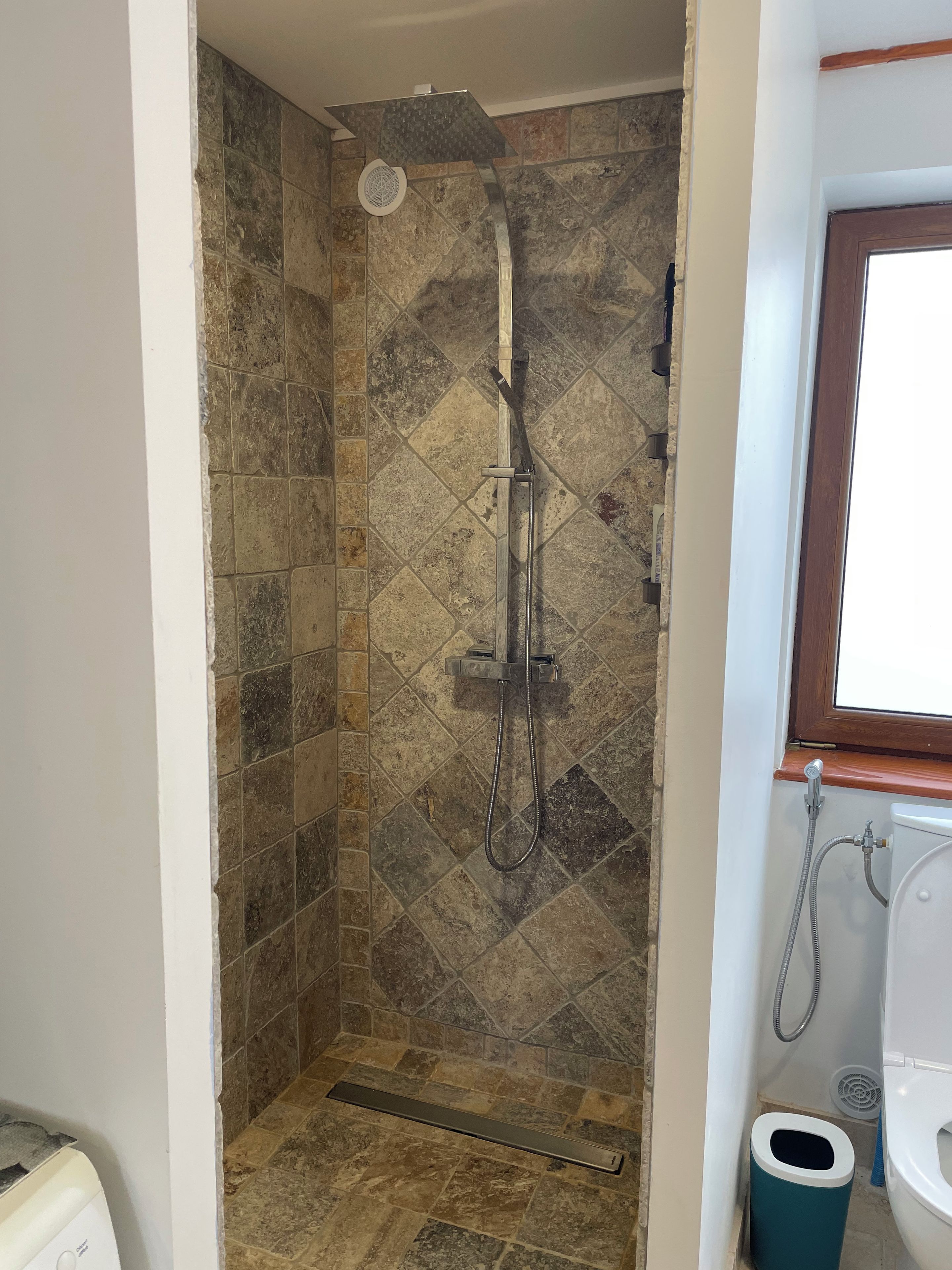 Un espace douche équipé d’un pommeau de douche à pluie, d’un pommeau de douche à main et d’un flexible de douche à main.