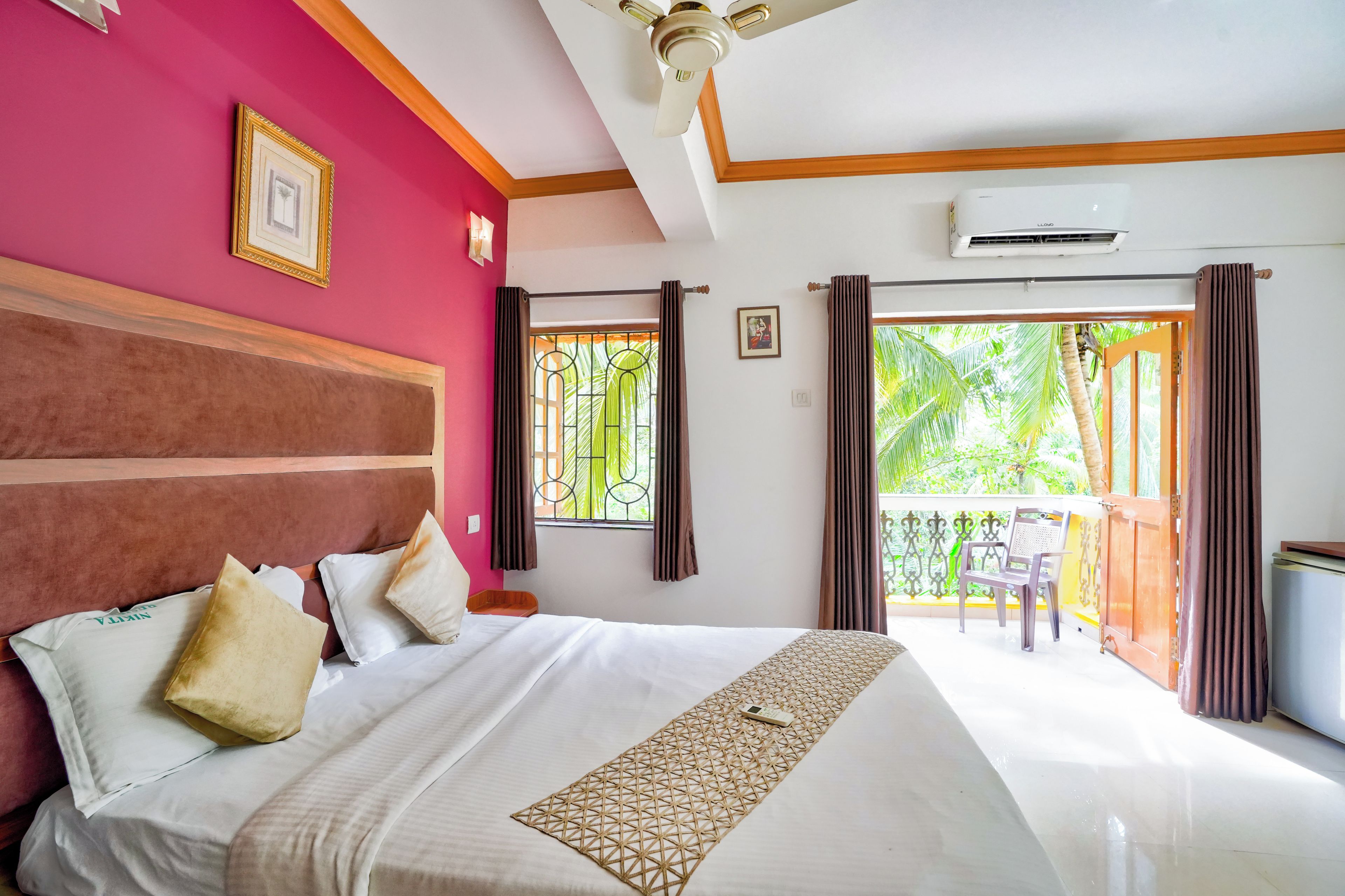 Ein Hotelzimmer mit Bett, Deckenventilator, Klimaanlage und einem Balkon mit Stuhl.