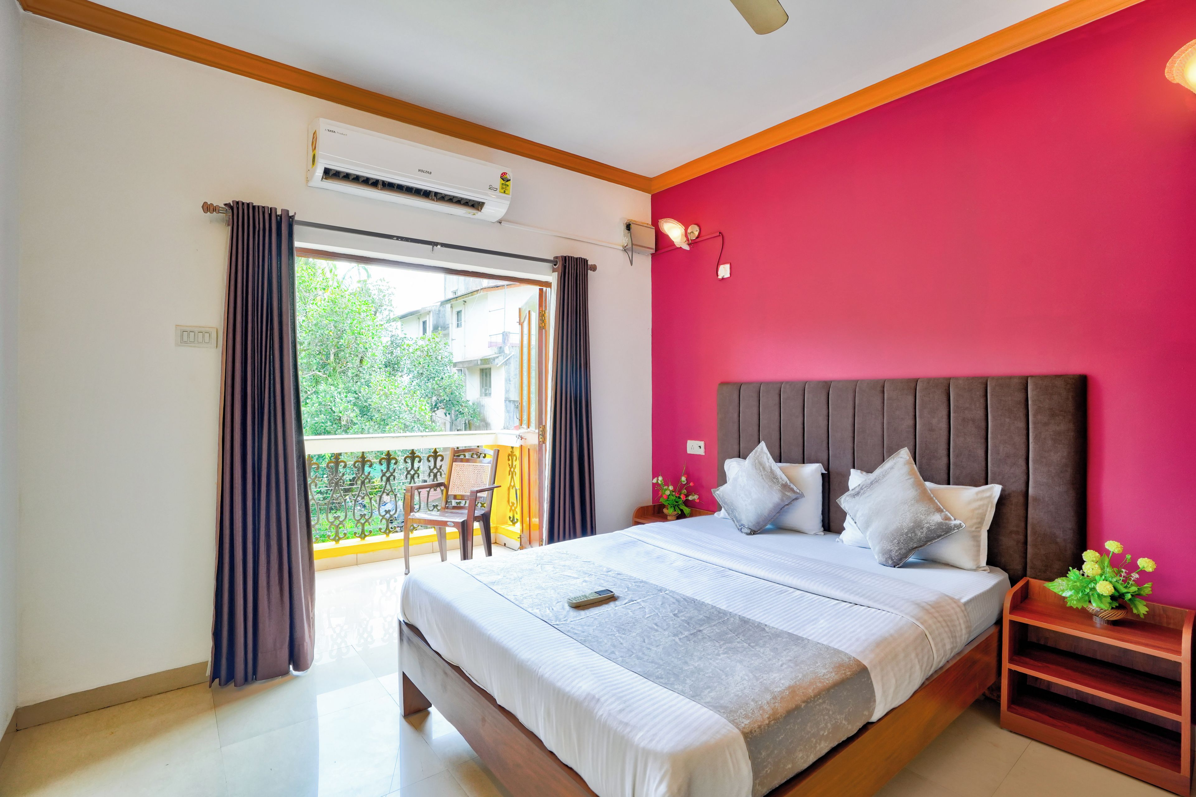 A bedroom with a bed, a nightstand, a window with curtains, and an air conditioning unit.
