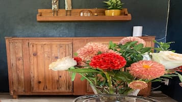 A wooden cabinet with a shelf above it, a glass vase with flowers, and a potted plant on the shelf.