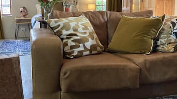 Ein braunes Ledersofa mit gemusterten Kissen, eine Vase mit Blumen und ein gemustertes Teppich.