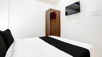 Quarto com cama, guarda-roupa, televisão de tela plana na parede e tomada.