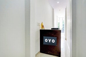 Un comptoir d'accueil avec une enseigne indiquant « OYO », situé dans un couloir aux murs blancs et au sol carrelé.