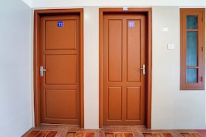 Dos puertas marrones con los números de habitación T1 y T2, un interruptor de luz y una ventana con marco de madera.