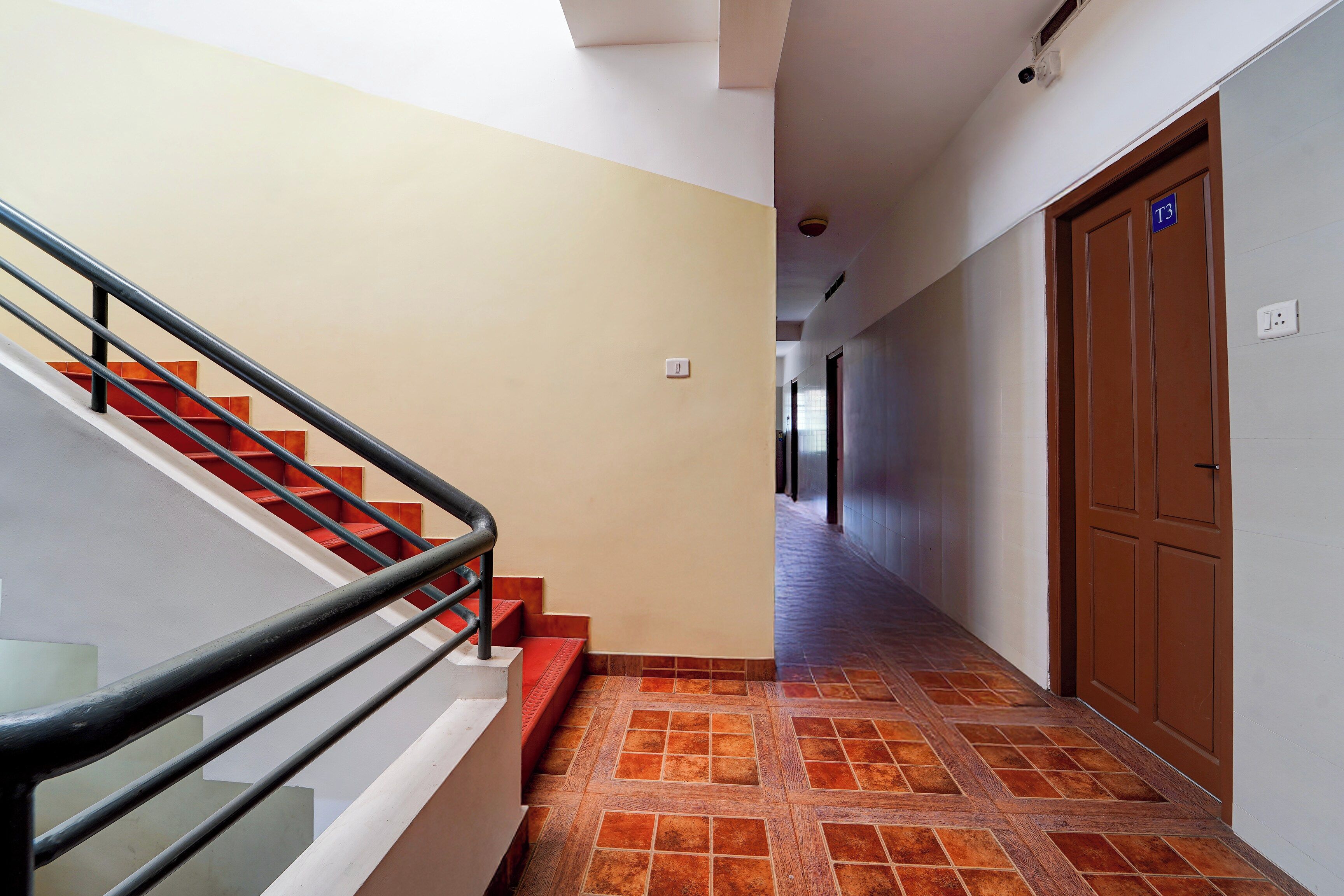 A hallway with a staircase, a door marked 'T3', and a tiled floor.