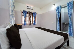 Een hotelkamer met een bed, een raam met gordijnen, een airconditioning en een badkamer met een wastafel.