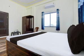 Une chambre d’hôtel équipée d’un lit, d’une armoire, d’une chaise, d’une petite table et d’un appareil de climatisation.