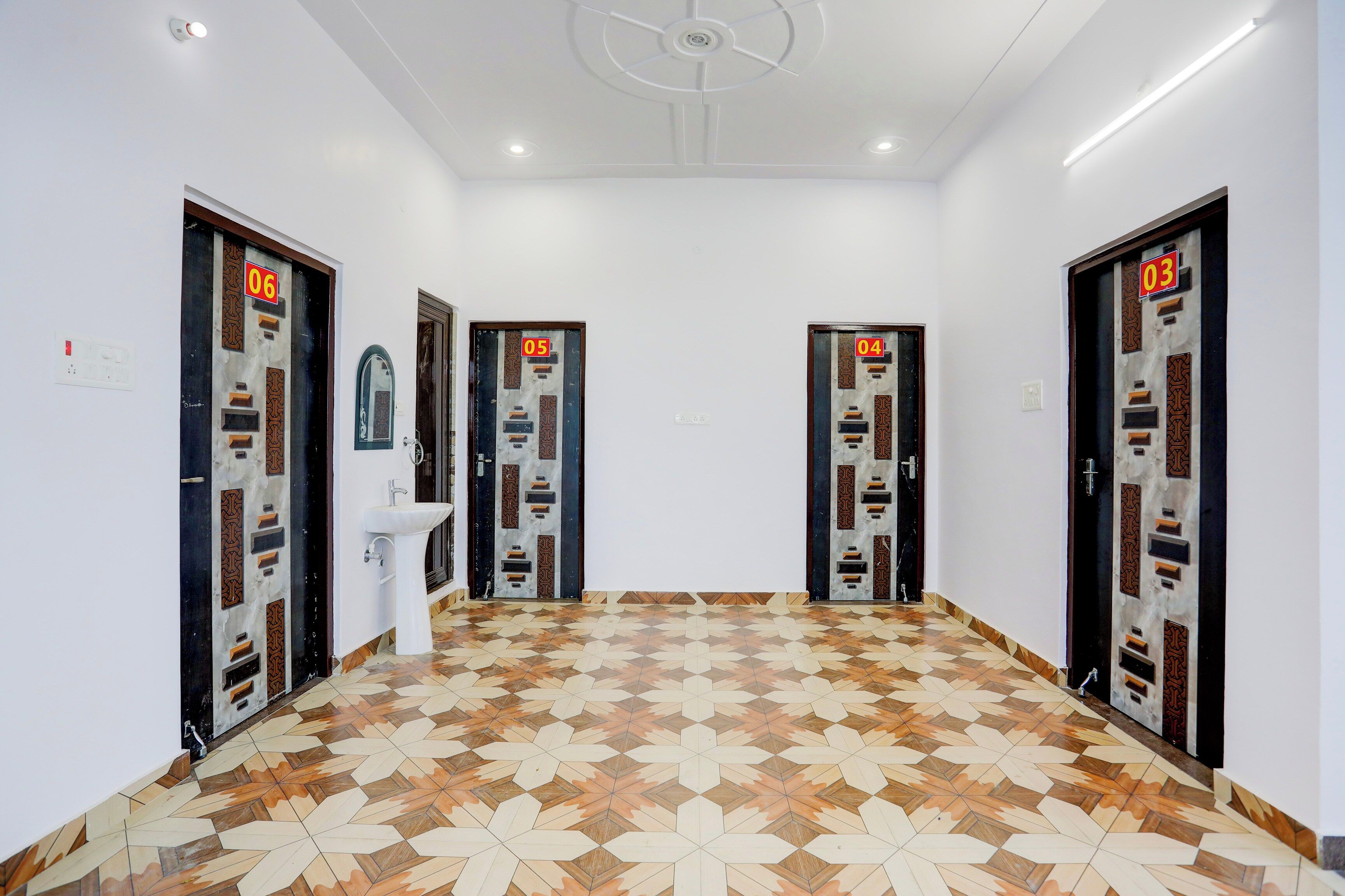 Un couloir avec des portes numérotées, un lavabo et un revêtement de sol à motifs.