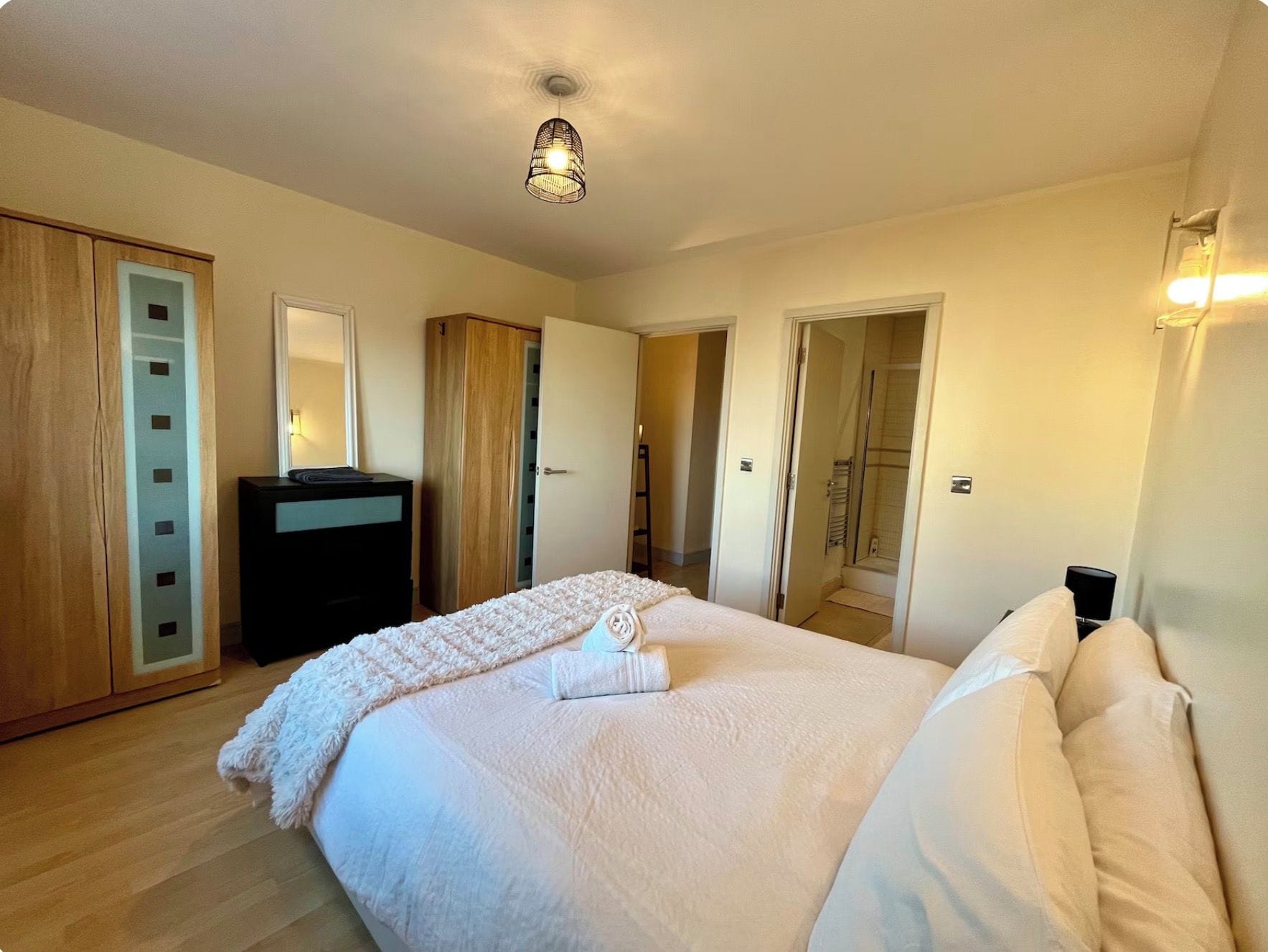 A bedroom with a bed, a wardrobe, a mirror, and a shower area.