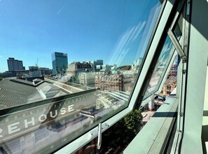 A view from a window with the word 'HOUSE' on the glass, overlooking a cityscape with various buildings and a clear sky. - Free Carpark Modern Lux 2 Bedroom Apt City Centre (Manchester)