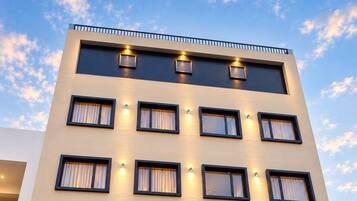 A hotel with a modern facade, multiple windows, and a reception area with a counter and plants.