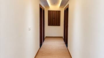 A hallway with wooden flooring, white walls, and a wooden door at the end.