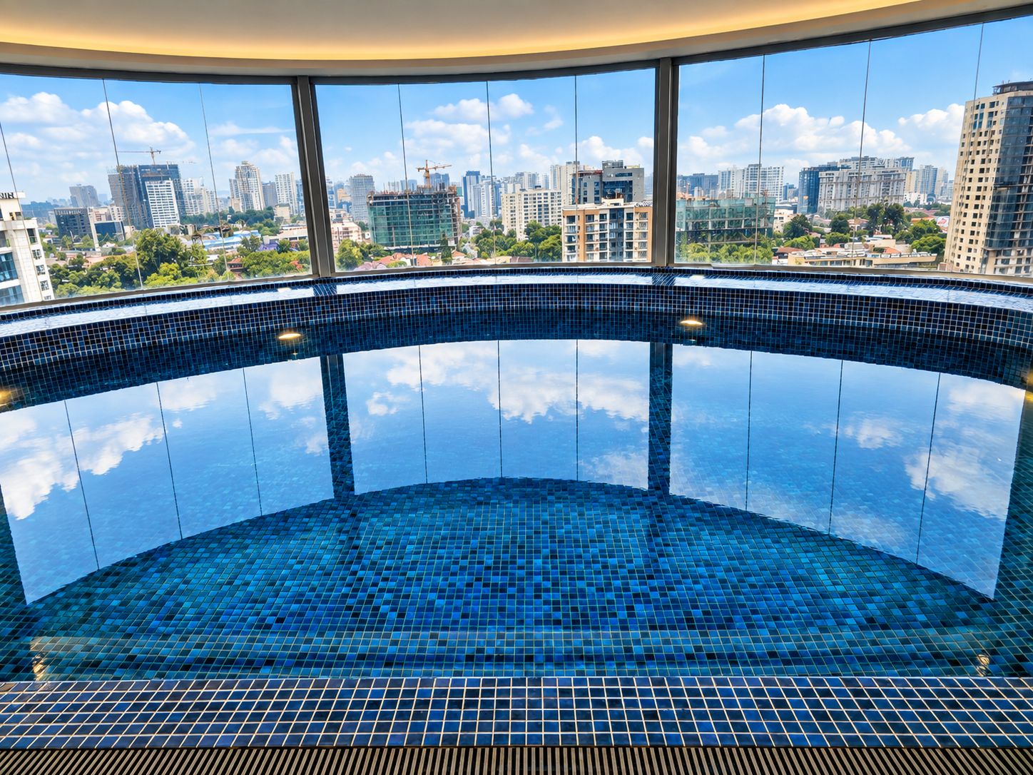 Ein kreisrunder Infinity-Pool mit Blick auf die Stadt durch große Fenster.