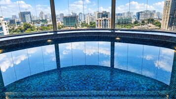 Une piscine à débordement circulaire offrant une vue sur le paysage urbain grâce à de grandes fenêtres.