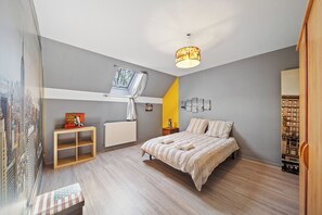Een slaapkamer met een bed, een raam met gordijnen, een radiator, een plank en een nachtkastje.