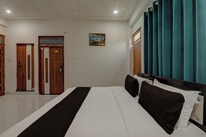 Une chambre d’hôtel avec un lit, une porte, un tableau et des rideaux.