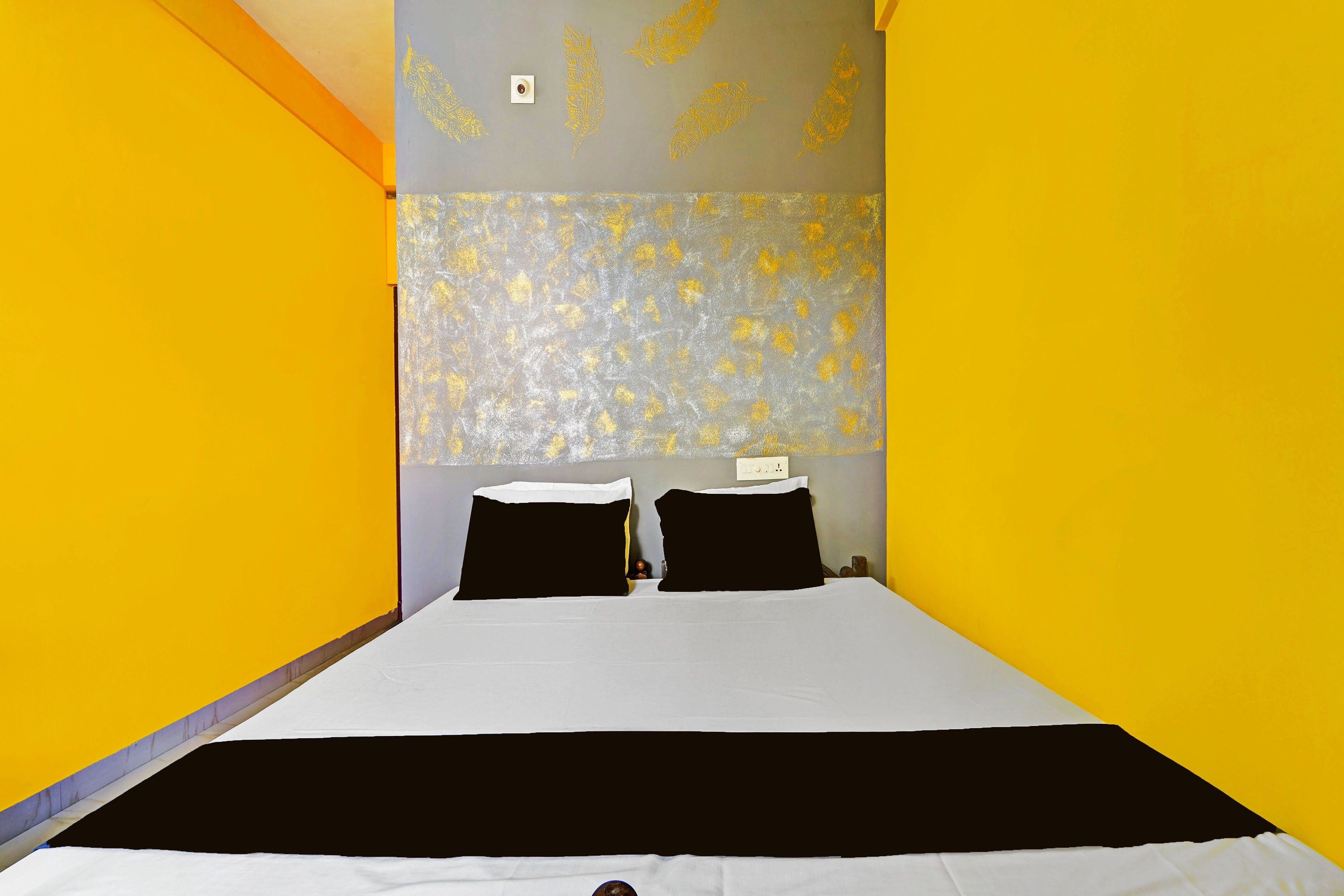 Een hotelkamer met een bed, twee zwarte kussens, een wit sprei en een gestreept hoofdbord.
