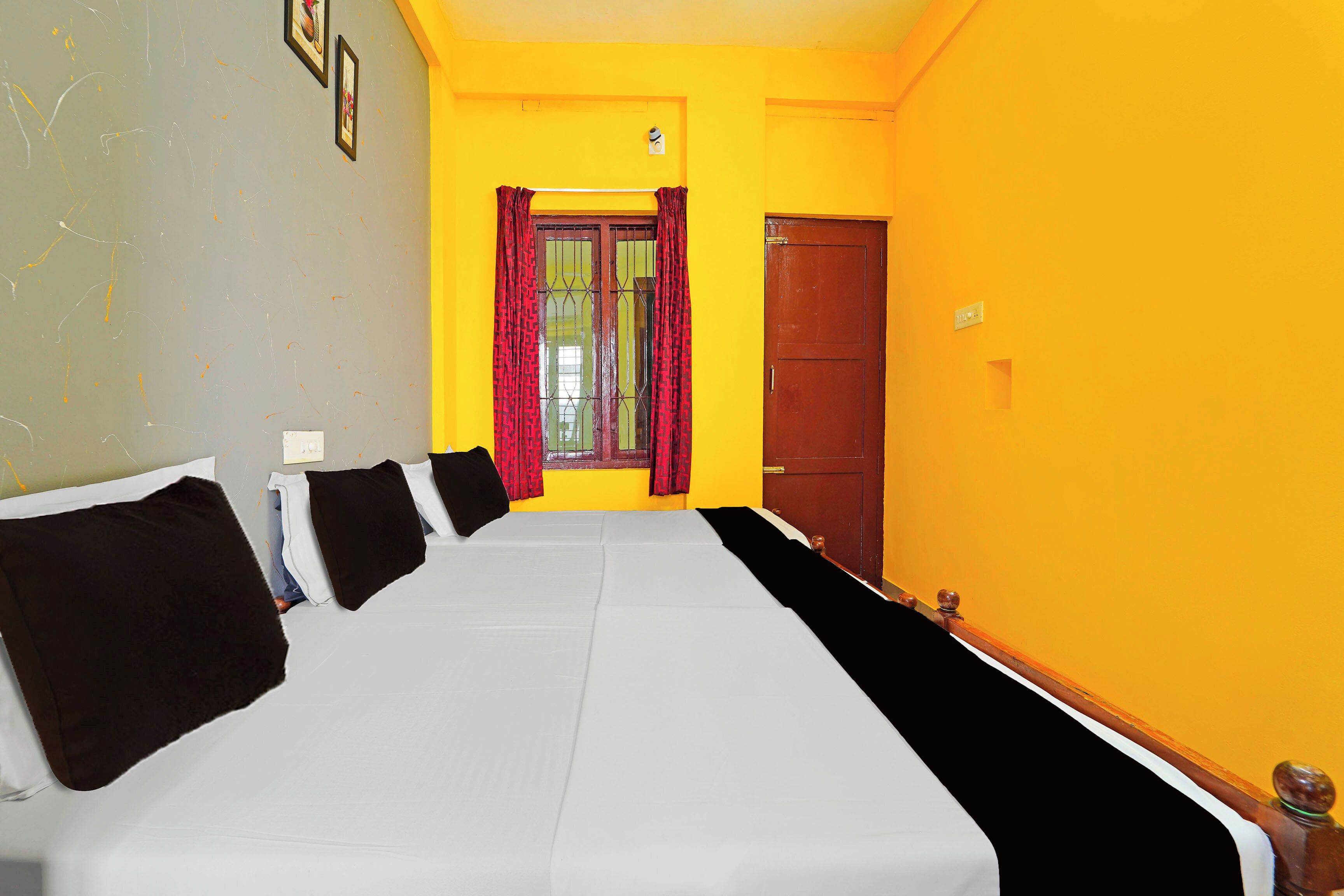 Una habitación con una cama grande, una puerta y un ventanal con cortinas.