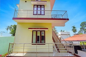 A two-story building with a balcony, a staircase, and a window with an air conditioning unit. - Hotel O Sivaganga Guest House (Trivandrum)