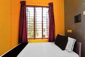 Ein Zimmer mit einem Bett, einem Vorhangfenster und einer Wand mit Dekorationen.