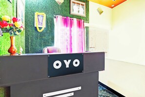 Una mesa de recepción con un letrero que dice 'OYO' y un cuadro enmarcado en la pared de fondo.