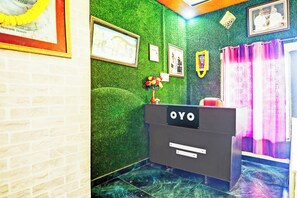 Un espace d’accueil agrémenté d’un mur végétal, d’un comptoir de réception portant l’inscription « OYO » et de tableaux encadrés accrochés au mur.