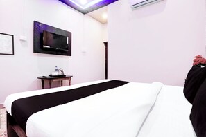 Une chambre d’hôtel avec un lit, un téléviseur à écran plat fixé au mur, une petite table avec un plateau et une bouteille d’eau.