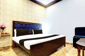 Une chambre d’hôtel avec un lit, une table de chevet, une chaise et un mur décoré de motifs.