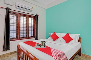 Una habitación de hotel con una cama, un ventanal con cortinas, aire acondicionado y una pared color verde azulado.