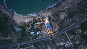 Vista aérea de una propiedad costera con varias construcciones, una playa y una carretera.