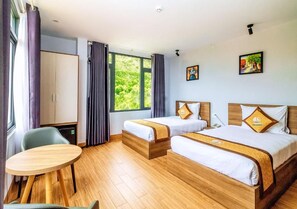 Une chambre d’hôtel avec deux lits, un plancher en bois, une table à manger et une vue sur la verdure.