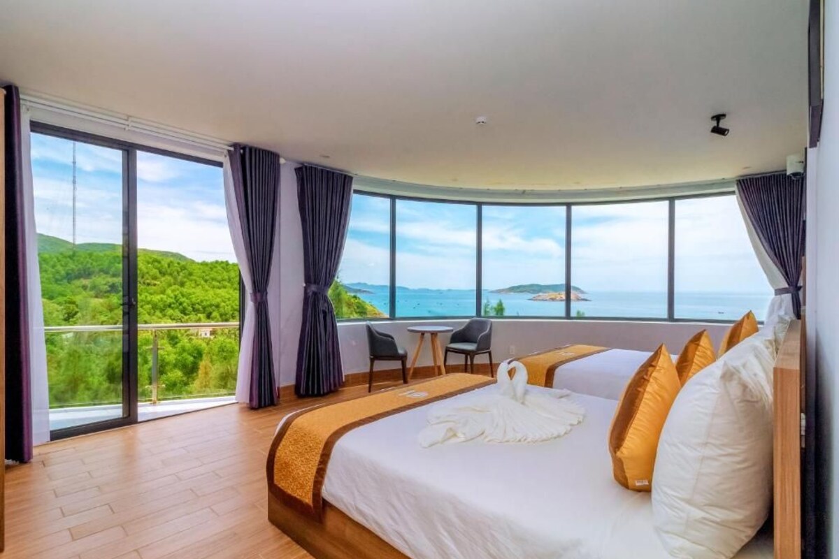 Une chambre d’hôtel avec un grand lit, une vue sur la mer et un balcon.