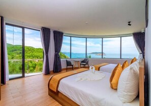Une chambre d’hôtel avec un grand lit, une vue sur la mer et un balcon.