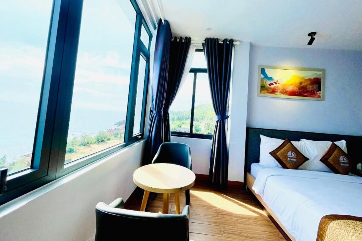 Une chambre d’hôtel avec un lit, une petite table, une chaise et un tableau au mur.